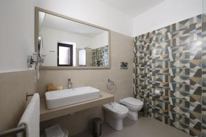 bagno con lavandino, servizi igienici e specchio di Hotel Villa Cute - HVC a Città di Lipari
