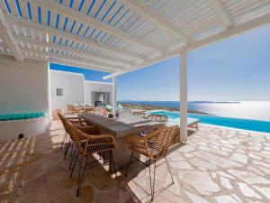 Un patio con mesa y sillas y el mar. en Villa Prive 77 Mykonos, en Mykonos ciudad