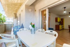 una mesa blanca con sillas blancas y un jarrón de flores en Appartamento Trieste Trilo 2 - MyHo Casa, en Alba Adriatica
