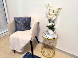 einen Stuhl und eine Vase mit Blumen auf dem Tisch in der Unterkunft MAR ROSA, estacionamento gratuito in Nazaré