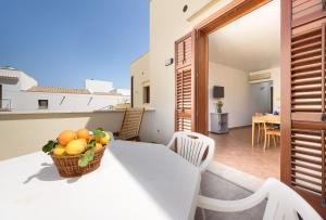 a basket of fruit on a white table on a balcony at I Tre Golfi - Covo dei Pirati in San Vito lo Capo