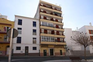 a tall white building with balconies on a street at Apartment Capuchinos in Málaga