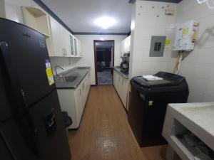 a kitchen with a black refrigerator and a sink at Bello y amplio apartamento cerca al aeropuerto in Pereira