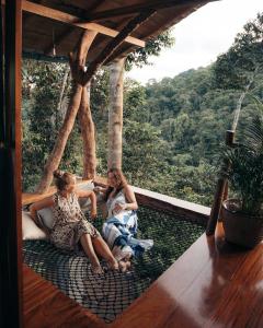 three women sitting on a porch with a view of a forest at Wild Wasi Lodge - Adventures - Guided Tours in Puyo