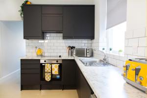 a kitchen with black cabinets and a sink at 4 Bedrooms Spacious House With 2 Bathrooms Free Parking - sleeps up to 10 guests in Liverpool +53 photos