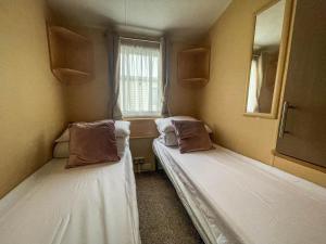 two beds in a small room with a window at Lovely 8 Berth Caravan At California Cliffs Holiday Park In Norfolk Ref 50053c in Great Yarmouth