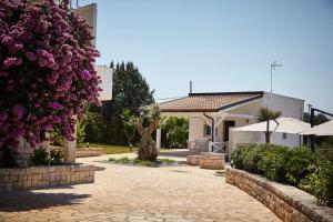 卡斯特拉納格羅泰的住宿－Villa D'Aprile Exclusive Luxury Villa with pool, Jacuzzi, SPA，车道上两朵大紫色花的房子
