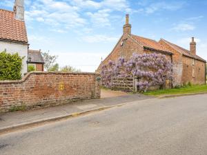 un edificio de ladrillo con flores púrpuras a un lado en Wisteria Cottage - Uk46478 en Hemingby