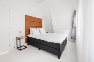 uma cama num quarto branco com piso branco em YAYS Amsterdam Salthouse Canal by Numa em Amesterdão