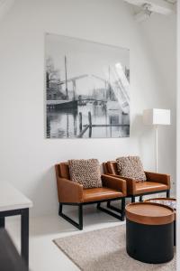 two chairs in a living room with a painting on the wall at YAYS Amsterdam Salthouse Canal by Numa in Amsterdam