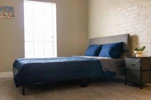 a bedroom with a bed with blue pillows and a brick wall at Cozy Retreat in Houston Galleria in Houston