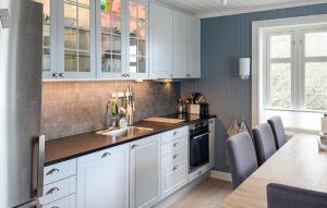 uma cozinha com armários brancos, um lavatório e uma mesa em Amazing Home In Skjrhalden With Kitchen em Skjærhollen