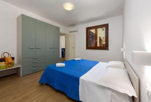 a white bedroom with a blue bed and a mirror at I Tre Golfi - Covo dei Pirati in San Vito lo Capo