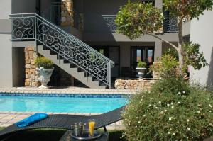 a swimming pool with a staircase next to a house at Stone Olive in Jeffreys Bay