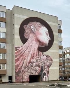 a mural of a woman on the side of a building at Warm Apartament Nou in Bacău