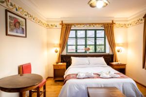 a bedroom with a bed and a table and a window at Hospedaje La Florida in Urubamba