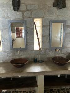 two sinks in a stone bathroom with two mirrors at Nosy Komba Lodge in Nosy Komba