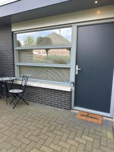 une porte coulissante en verre menant à une terrasse avec une table et une chaise. dans l'établissement B&B Twente, à Enschede