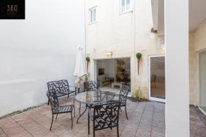 un patio con mesa de cristal y sillas en 4BR Home in Prime Location Just Off the Promenade by 360 Estates, en Sliema