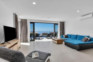 a living room with a blue couch and a television at Ferienhaus Komplex - Villa Oliver - Makarska Exklusiv in Veliko Brdo