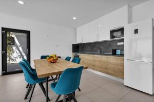 a kitchen with a wooden table and blue chairs at Ferienhaus Komplex - Villa Oliver - Makarska Exklusiv in Veliko Brdo