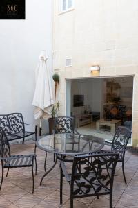un patio con mesa de cristal, sillas y chimenea en 4BR Home in Prime Location Just Off the Promenade by 360 Estates, en Sliema