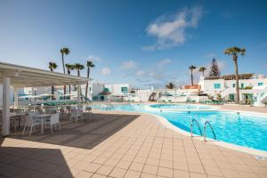 カレタ・デ・フステにあるSmy Tahona Fuerteventuraのリゾートの隣にあるスイミングプール(テーブル、椅子付)