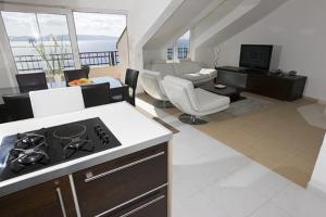 a kitchen with a stove and a living room at Apartments Gudelj in Podgora