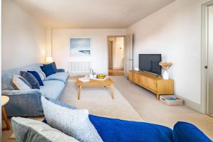 a living room with blue couches and a tv at White Horses - Sleeps 2 by Big Skies Cottages in Blakeney