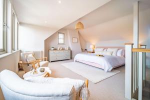 a white bedroom with a bed and a chair at White Horses - Sleeps 2 by Big Skies Cottages in Blakeney