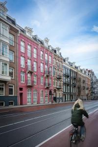 una mujer montando una bicicleta por una calle con edificios en Krisotel, en Ámsterdam