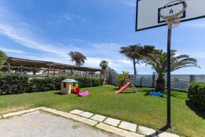 un patio trasero con un aro de baloncesto y un parque infantil en Rocca dei Tramonti Apartments en Punta Braccetto