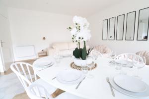 a white dining room with a white table and chairs at La Bohème By Plaza in Serris
