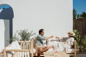 a man and woman sitting on a patio drinking wine at The Carobs Villas in Carvoeiro