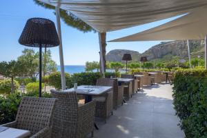 an outdoor dining area with tables and chairs and the ocean at Porto Angeli in Archangelos