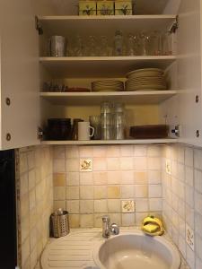 a bathroom with a sink and shelves with dishes at les sables d'or grau du roi in Le Grau-du-Roi +30 photos