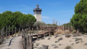 a lighthouse on a beach with a wooden bridge at les sables d'or grau du roi in Le Grau-du-Roi