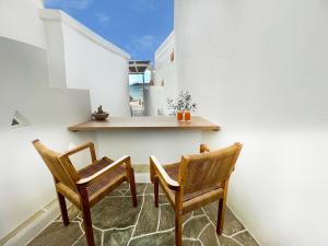 two chairs and a table in a room with the ocean at Lemonia Rooms 1 in Platis Yialos Sifnos