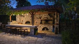 cocina al aire libre con taburetes y chimenea de piedra en Villa Petra, en Kalamaki Messinia