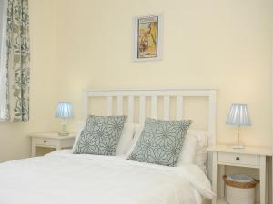 a bedroom with a white bed with two tables and two lamps at Sea Drift in St Austell