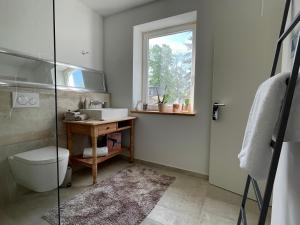 ein Bad mit einem Waschbecken, einem WC und einem Fenster in der Unterkunft PauliDrei in Leipzig