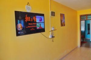 Habitación amarilla con TV en la pared en Shanzu Budget Traveler Homestay, en Mombasa