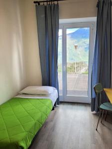 sypialnia z zielonym łóżkiem przed oknem w obiekcie Hotel Panorama w mieście Riva del Garda