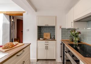 a kitchen with white cabinets and green subway tiles at Wellies in Appledore