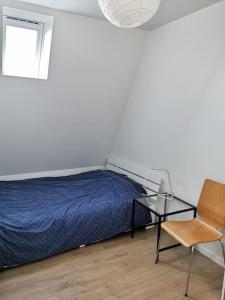 een slaapkamer met een bed, een stoel en een tafel bij Joli 2 pièces lumineux tout neuf in Clichy