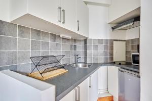 una cocina con armarios blancos y fregadero en Charming 1 bedroom apartment Le Marais by Studio Prestige, en París