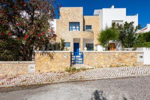 a house with a blue door and a stone wall at Casa do Sol by AcasaDasCasas in Ericeira