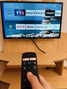 a person holding a remote control in front of a tv at Kyriad Paris Sud Les Ulis Courtaboeuf in Les Ulis