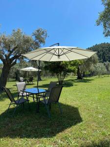 a table and chairs under an umbrella in a field at Meerithic ROKKA ROOMS in Vourvourou