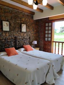 two beds in a bedroom with a stone wall at Hospedaje Vega in Santillana del Mar